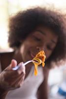 una giovane donna afroamericana che mangia pasta foto