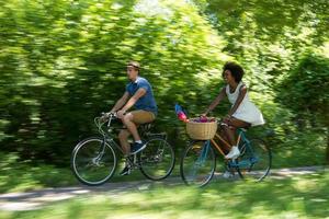 giovane coppia multietnica che fa un giro in bicicletta nella natura foto