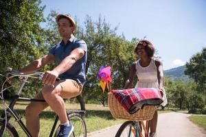 giovane coppia multietnica che fa un giro in bicicletta nella natura foto