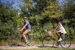 giovane coppia multietnica che fa un giro in bicicletta nella natura foto