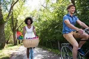 giovane coppia multietnica che fa un giro in bicicletta nella natura foto