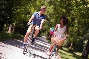 giovane coppia multietnica che fa un giro in bicicletta nella natura foto