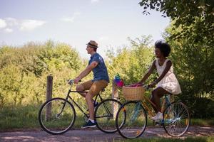 giovane coppia multietnica che fa un giro in bicicletta nella natura foto