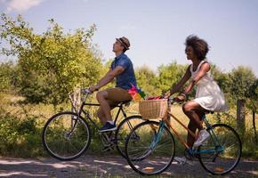 giovane coppia multietnica che fa un giro in bicicletta nella natura foto