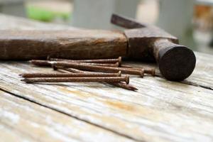 martello e chiodi su fondo di legno, testa di legno e ruggine martello di ferro sdraiato su tavola di legno con officina all'aperto. foto