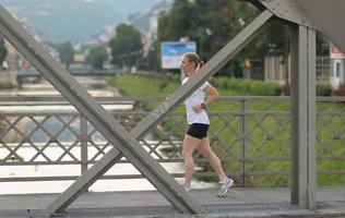 donna sportiva che corre sul marciapiede foto