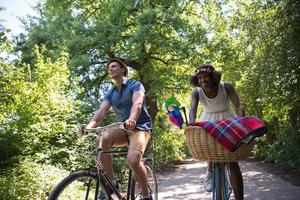 giovane coppia multietnica che fa un giro in bicicletta nella natura foto