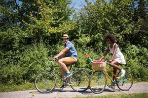 giovane coppia multietnica che fa un giro in bicicletta nella natura foto