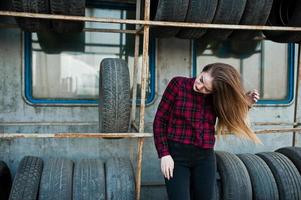 giovane ragazza hipster in camicia a scacchi nella zona di montaggio dei pneumatici. foto