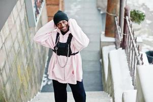 elegante uomo afroamericano in stile urbano in felpa con cappuccio rosa posato al giorno d'inverno. foto