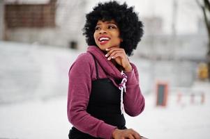 capelli ricci donna afroamericana posata al giorno d'inverno, seduta su una panchina. foto