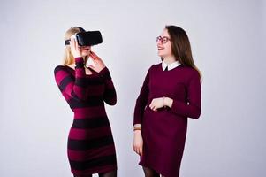 due ragazze in abiti viola che provano occhiali per realtà virtuale in studio. foto