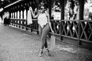 ragazza afroamericana casual con borse della spesa colorate che camminano all'aperto. shopping alla moda della donna di colore. foto