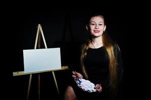 bella donna artista pittore con spazzole e tela ad olio in posa in studio isolato su nero. foto