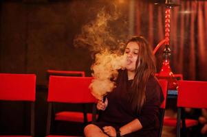 ragazza asiatica che fuma narghilè al lounge bar. foto