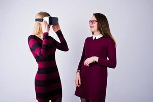 due ragazze in abiti viola che provano occhiali per realtà virtuale in studio. foto