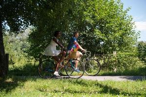 giovane coppia multietnica che fa un giro in bicicletta nella natura foto