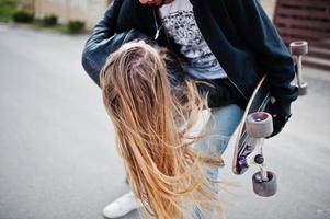 bella coppia multirazziale che cammina insieme al longboard. foto