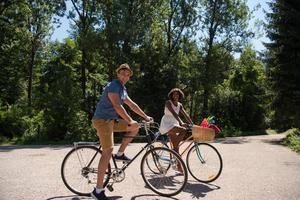 giovane coppia multietnica che fa un giro in bicicletta nella natura foto