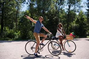 giovane coppia multietnica che fa un giro in bicicletta nella natura foto