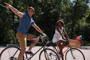 giovane coppia multietnica che fa un giro in bicicletta nella natura foto