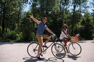 giovane coppia multietnica che fa un giro in bicicletta nella natura foto