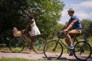 giovane coppia multietnica che fa un giro in bicicletta nella natura foto