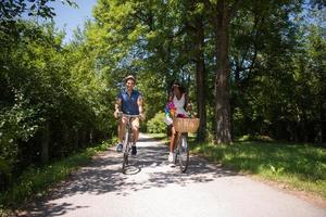 giovane coppia multietnica che fa un giro in bicicletta nella natura foto