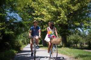 giovane coppia multietnica che fa un giro in bicicletta nella natura foto