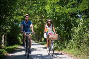 giovane coppia multietnica che fa un giro in bicicletta nella natura foto