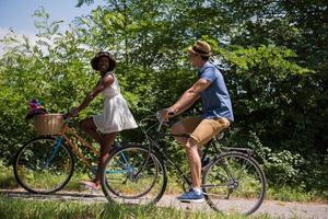 giovane coppia multietnica che fa un giro in bicicletta nella natura foto