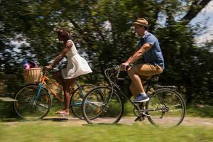 giovane coppia multietnica che fa un giro in bicicletta nella natura foto