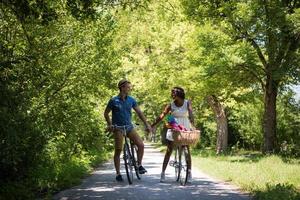 giovane coppia multietnica che fa un giro in bicicletta nella natura foto