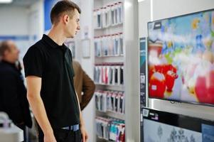 venditore uomo consulente professionale in negozio di tecnologia o stand vicino a smart tv. foto