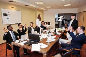 riunione del team aziendale multirazziale attorno al tavolo della sala riunioni, due leader del team lanciano carta. foto