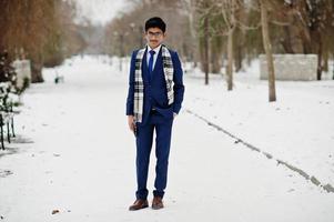 elegante studente indiano uomo in giacca e cravatta, occhiali e sciarpa poste al giorno d'inverno all'aperto. foto