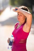 donna che beve acqua da una bottiglia dopo aver fatto jogging foto