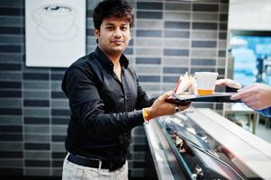 il cameriere cassiere dà l'ordine sul vassoio del cibo a un uomo indiano alla moda. foto