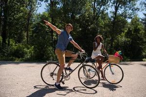 giovane coppia multietnica che fa un giro in bicicletta nella natura foto