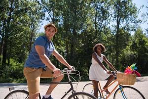 giovane coppia multietnica che fa un giro in bicicletta nella natura foto