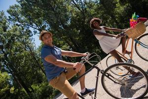 giovane coppia multietnica che fa un giro in bicicletta nella natura foto