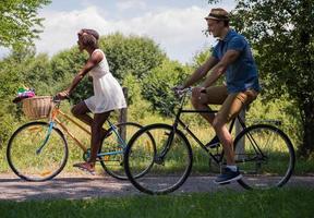 giovane coppia multietnica che fa un giro in bicicletta nella natura foto