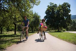 giovane coppia multietnica che fa un giro in bicicletta nella natura foto