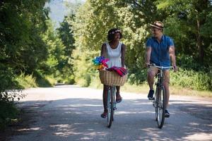 giovane coppia multietnica che fa un giro in bicicletta nella natura foto