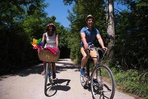 giovane coppia multietnica che fa un giro in bicicletta nella natura foto