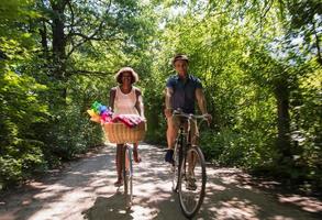 giovane coppia multietnica che fa un giro in bicicletta nella natura foto