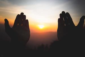 silhouette delle mani dell'uomo cristiano che pregano Dio, l'uomo prega per la benedizione di Dio per desiderare una vita migliore. implorare perdono e credere nella bontà, sfondo del concetto di religione cristiana. foto