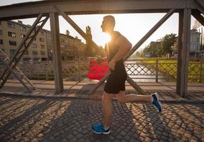 uomo che fa jogging attraverso il ponte al mattino soleggiato foto