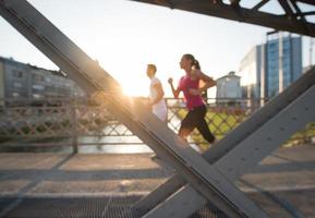 giovane coppia che fa jogging attraverso il ponte della città foto