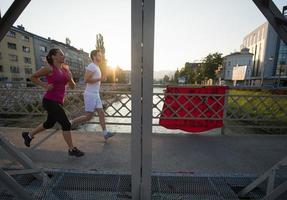 giovane coppia che fa jogging attraverso il ponte della città foto